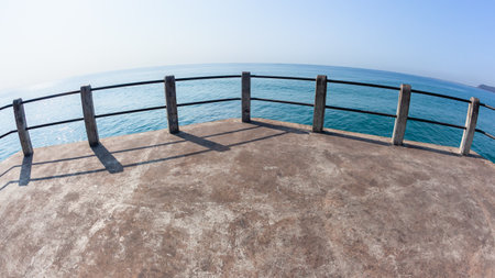 Beach Pier hand railing standing middle of  jetty towards clear blue ocean horizon sea waters a tropical weather landscape.の写真素材