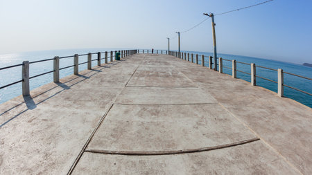 Beach standing middle of public pier jetty towards clear blue ocean horizon sea waters a tropical weather landscape.の写真素材