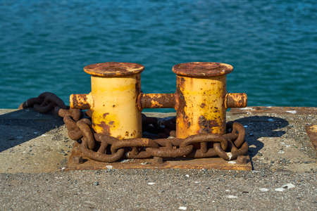 A double bitt mooring bollard with a heavy chain around it.の写真素材