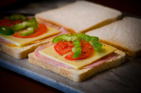 Ham sandwiches with cheese, tomato and green pepper.の写真素材
