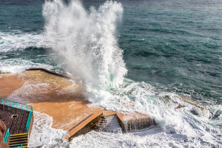 A stunning view of waves crashing dramatically against the coastal structures in Funchal, Madeira, showing the raw beauty of the Atlantic Oceanの写真素材