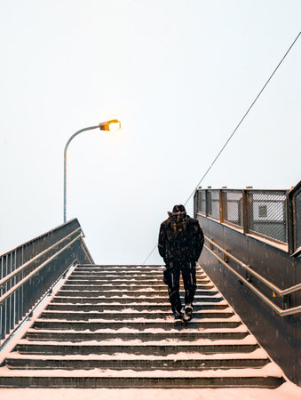 A man walking up a staircase covered with snow (Rostock, Germany)