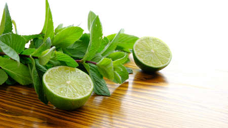 Green mint and fresh lime on the woodenbackground.