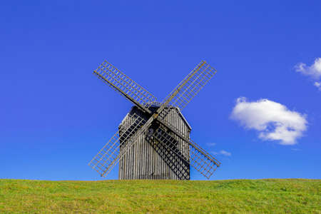 Traditional windmill on the grass against the sky with a cloud