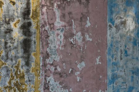 An old concrete wall painted yellow, pink and blueの写真素材