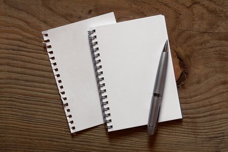 sprial notebook and pen on wooden desk 