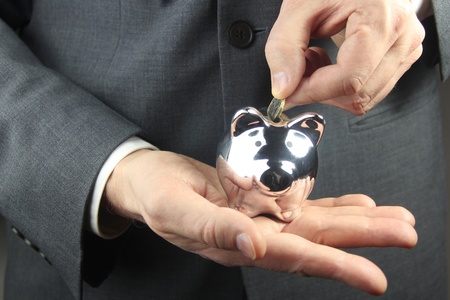 businessman putting coin into a piggy bankの写真素材