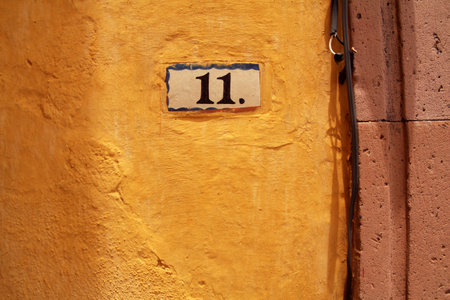 Number eleven on yellow wall, house address plate numberのeditorial素材
