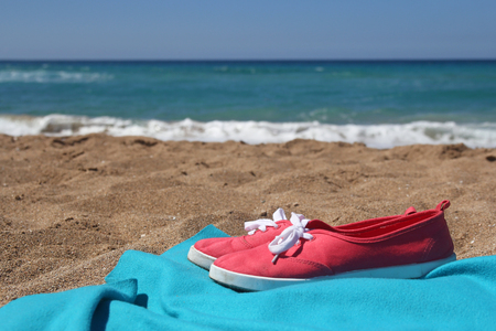 Red sneakers and blue blanket on beautiful beachの写真素材