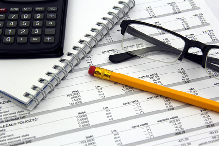 Pencil, calculator, glasses and notebook on billsの写真素材