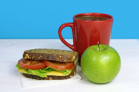 Healthy lunch with sandwich, green apple and coffee in red cupの写真素材