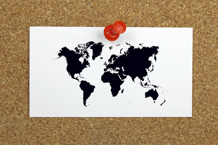 push pin holding a card with world map on a cork board の写真素材
