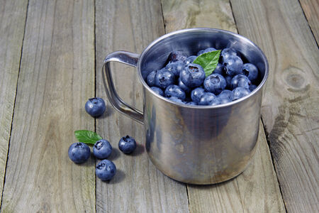 blueberries in metal cup on wooden backgroundの写真素材