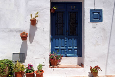 front side of typical spanish house with blue wooden door and fl の写真素材