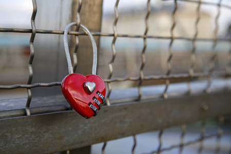 red heart-shaped love padlock chained to bridgeの写真素材