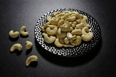 cashew nuts on plate on black backgroundの写真素材