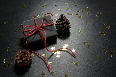 Christmas present with shiny golden stars and cones on a black backgroundの写真素材