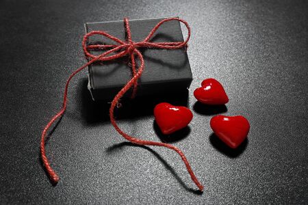 Valentine's gift with red ribbon and glass hearts on black backgroudnの写真素材