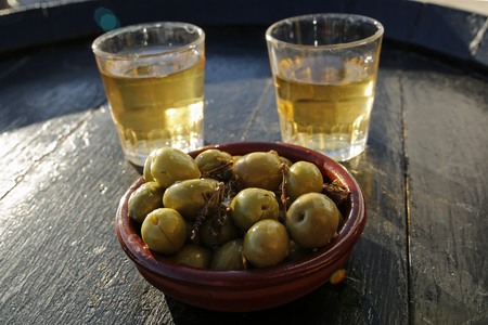 two glasses of white wine and green olives- typical spanish tapasの写真素材