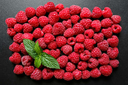 Fresh raspberries with mint leaf on black background
