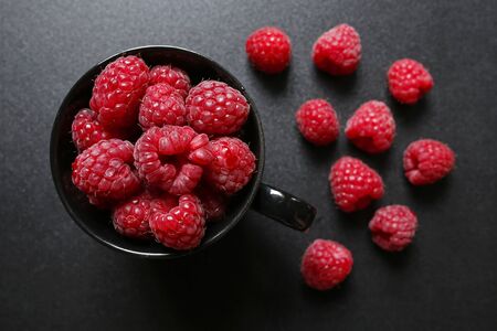 Fresh raspberries in a black cupの写真素材
