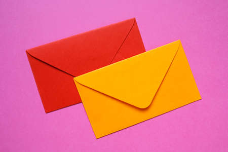 Red and orange envelopes on pink backgroundの写真素材