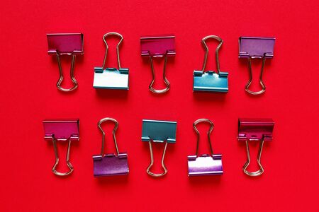 Flat lay regular composition of colorful paper clips on red backgroundの写真素材