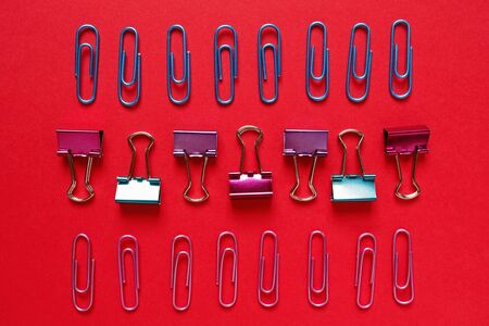Flat lay regular composition of colorful paper clips on red backgroundの写真素材