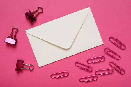 White envelope and paper clips on pink backgroundの写真素材