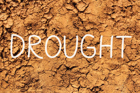 drought word written on dry soil backgroundの写真素材