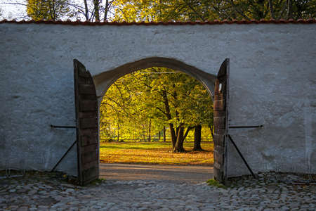 beautiful autumn park seen through open historic gate