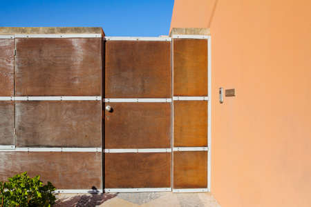 elegant wooden fence with door in orange wall and blue sky in the background