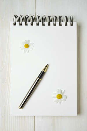 spiral notebook with pen and chamomile flowersの写真素材