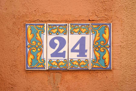 decorated ceramic tiles 24 house number on orange rough wallの写真素材