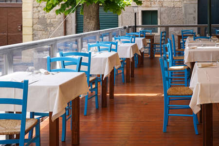 empty tables and blue chairs in outdoor restaurant