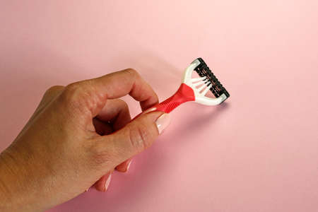 disposable shaving razor in a female hand on pink backgroundの写真素材