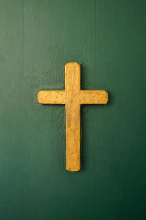 golden catholic cross on green wooden door