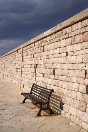bench next to stone breakwater at the portの写真素材