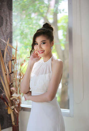 Head shot of beautiful attractive smiling woman in white wedding dress with bridal hair curl hairstyle.の写真素材
