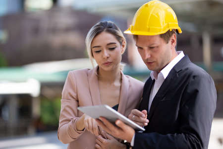 Female industrial engineer wearing a white helmet while standing in a construction site with...