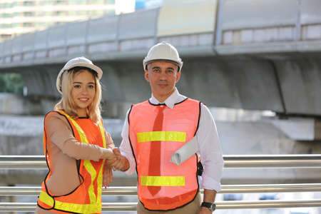 Female industrial engineer wearing a white helmet while standing in a construction site with...