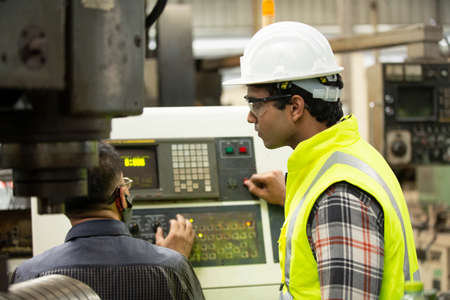 Technician and Engineers operating a cnc machine in factory