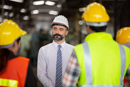 Male Industrial Engineers Talk with Factory Worker . They Work at the Heavy Industry Manufacturing Facility.の写真素材