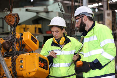 Men and female workers in factory operating machine in workshop floor.