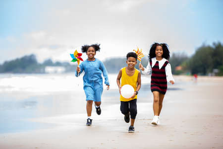 Kids playing running on sand at the beach, A group of children holding hands in a row on the beach...