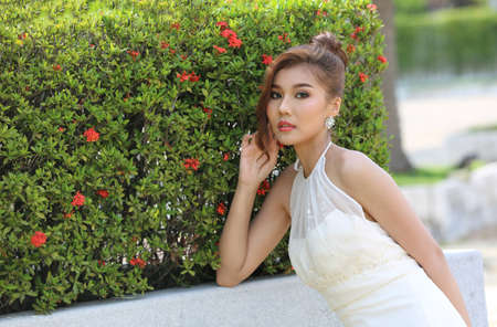 Portrait of Beautiful attractive bride in wedding dress with long full skirt sitting by poolside.の写真素材