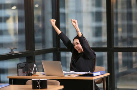Shot of young woman working at home with laptop and documents