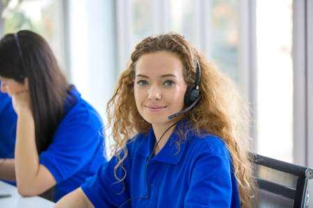 Call center staff in blue T-shirt accompanied by her team. Smiling customer staff support operator...
