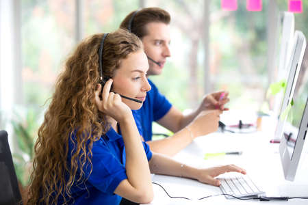 Call center staff in blue T-shirt accompanied by her team. Smiling customer staff support operator...