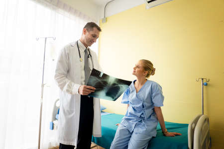 Doctor explaining lungs x-ray to women patient in clinic or Doctor in the office examining an x-ray...